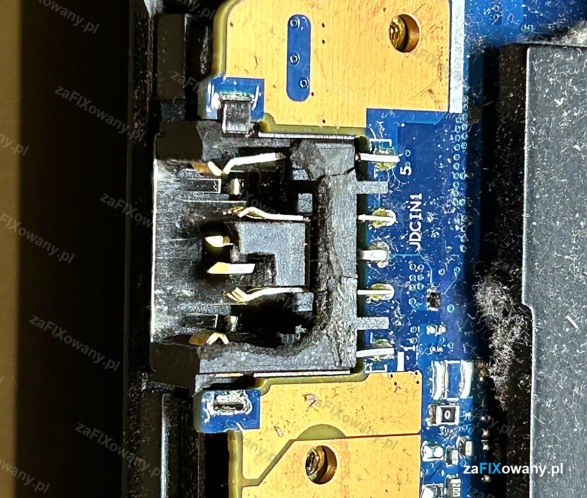 Zbliżenie gniazda zasilania JDCIN1 w Lenovo Legion Y540 z pękniętą obudową i wygiętymi stykami