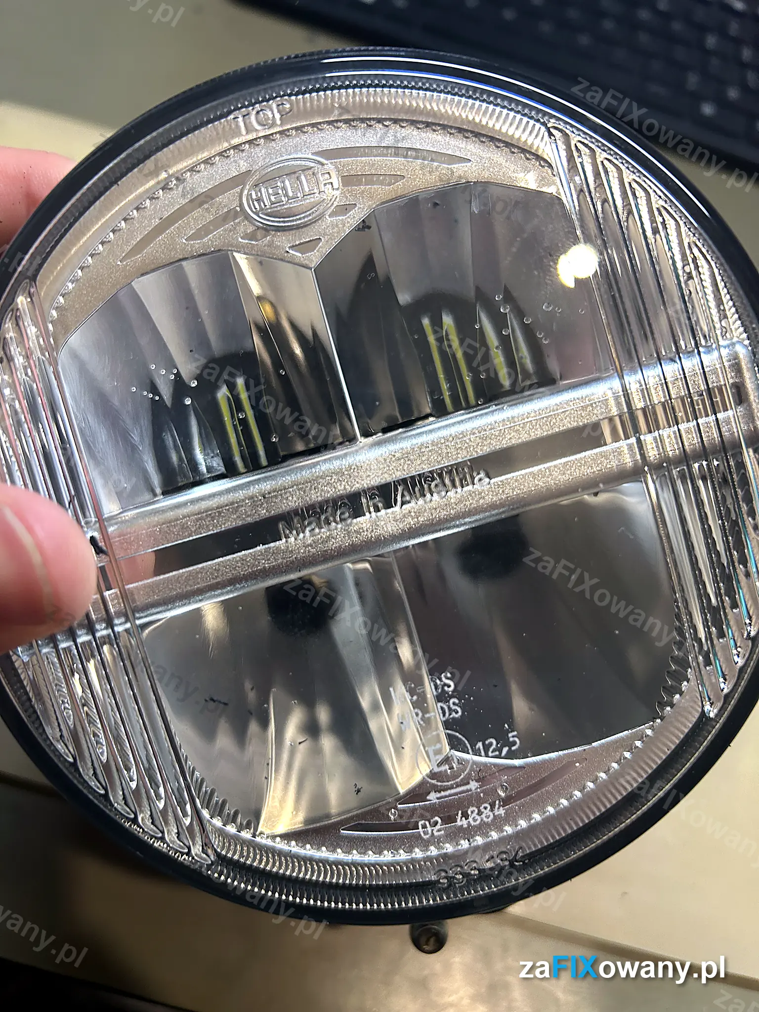 Okrągły reflektor LED HELLA z maszyny rolniczej, pod kloszem widoczne krople wody