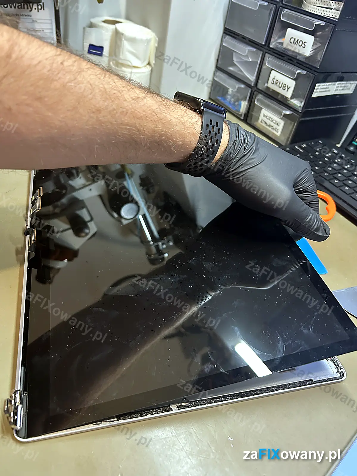 Serwisant w rękawiczkach wyjmuje stary ekran z Surface Laptop 3