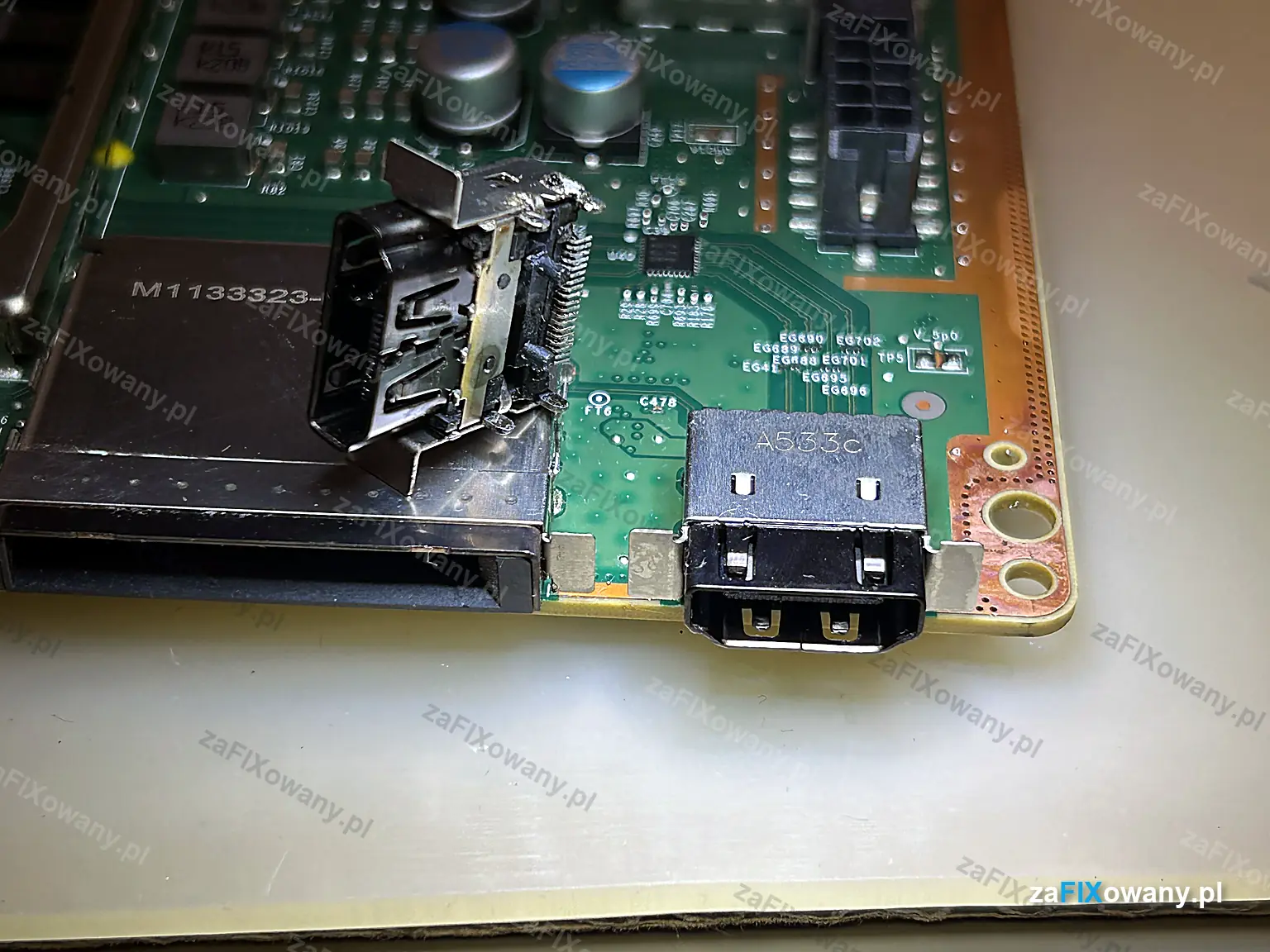 Płyta główna Xbox Series X z nowym portem HDMI, obok leży wylutowane uszkodzone gniazdo