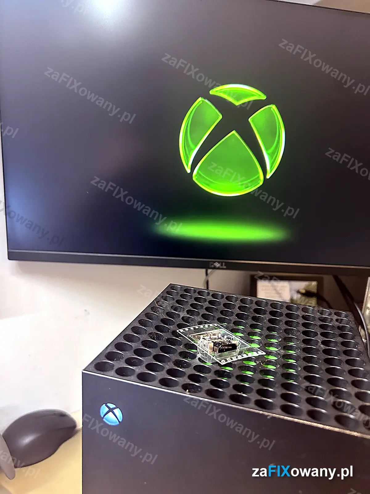 Xbox Series X po naprawie, na monitorze logo Xbox, na konsoli leży stary port HDMI