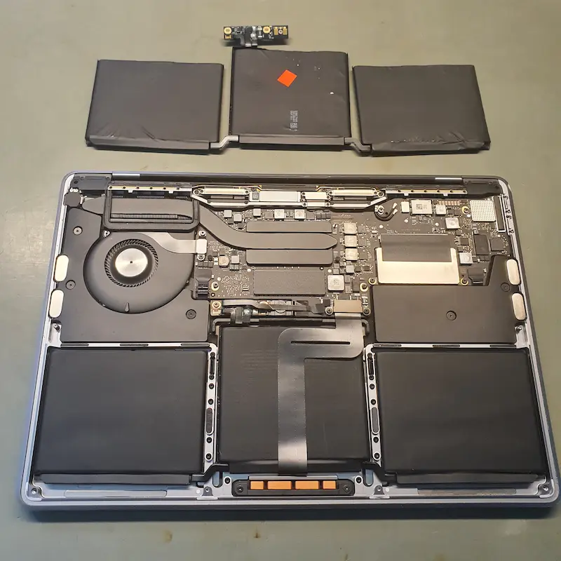 Widok na wnętrze otwartego MacBooka Pro podczas serwisu wymiany baterii.