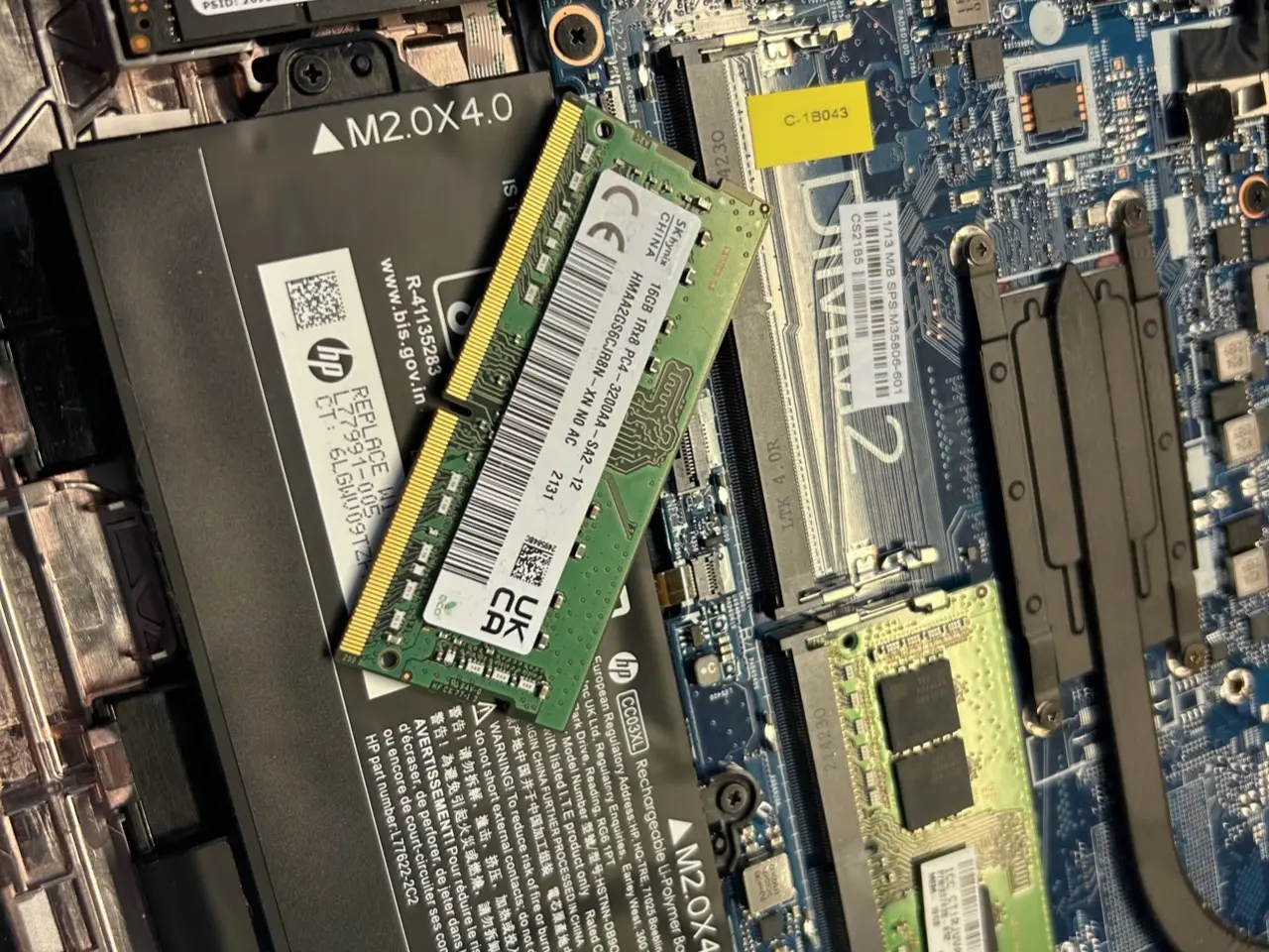 Laptop HP z otwartą obudową: moduł pamięci RAM 16 GB przed montażem obok gniazd pamięci