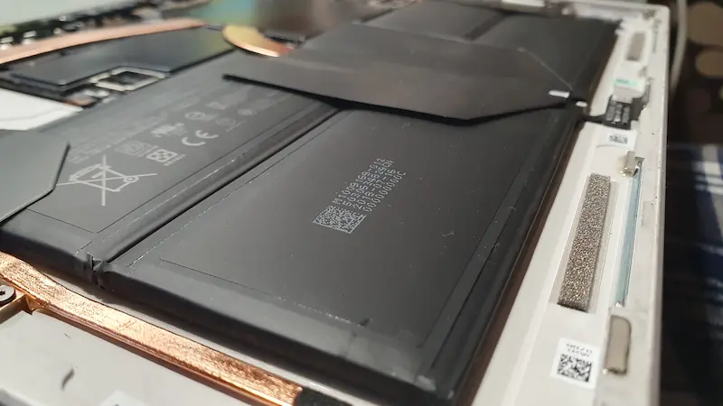 Technik w serwisie laptopów we Wrocławiu wymienia baterię w laptopie.